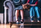 deux enfants avec un chien assis sur un canapé